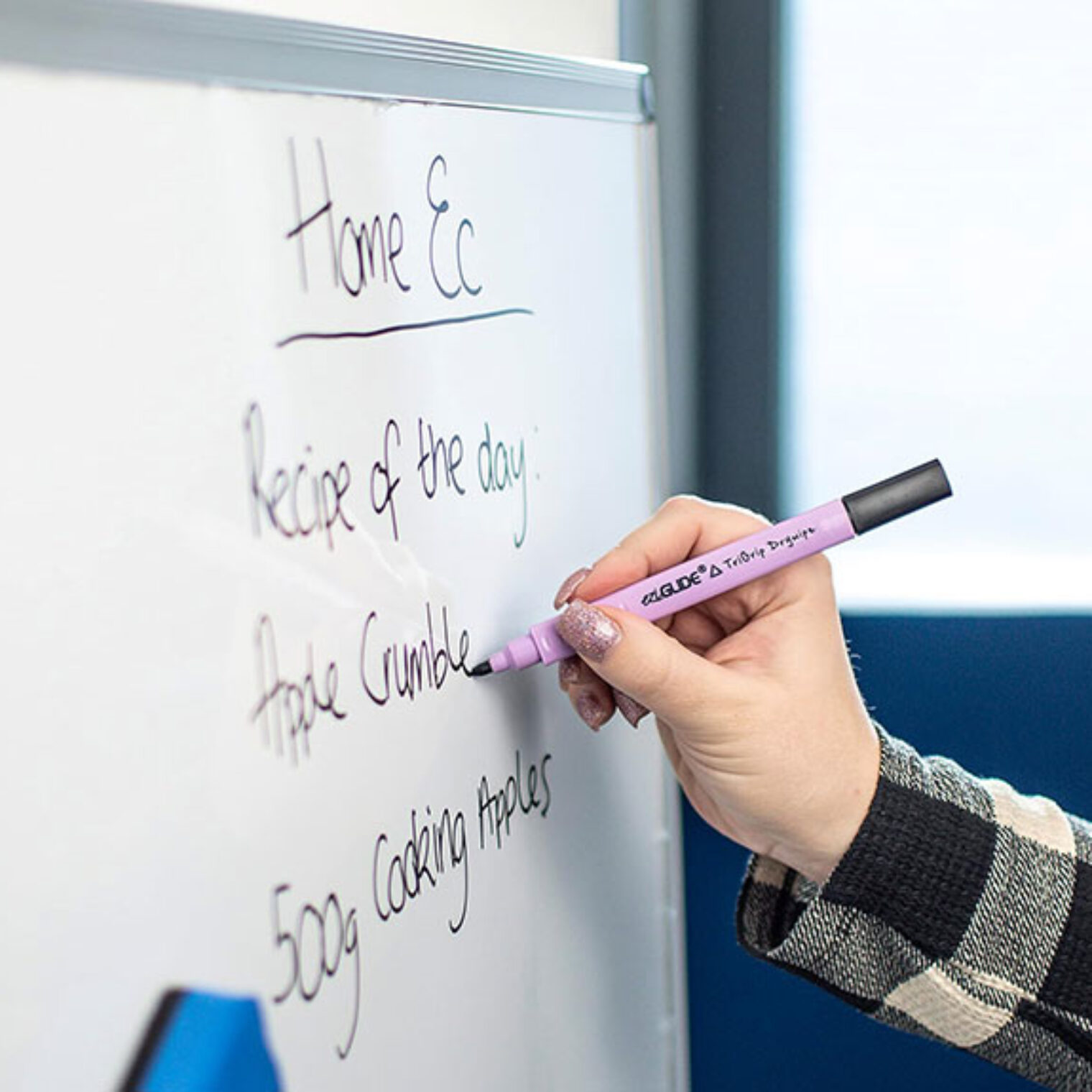 Hand holding pen, writing on whiteboard